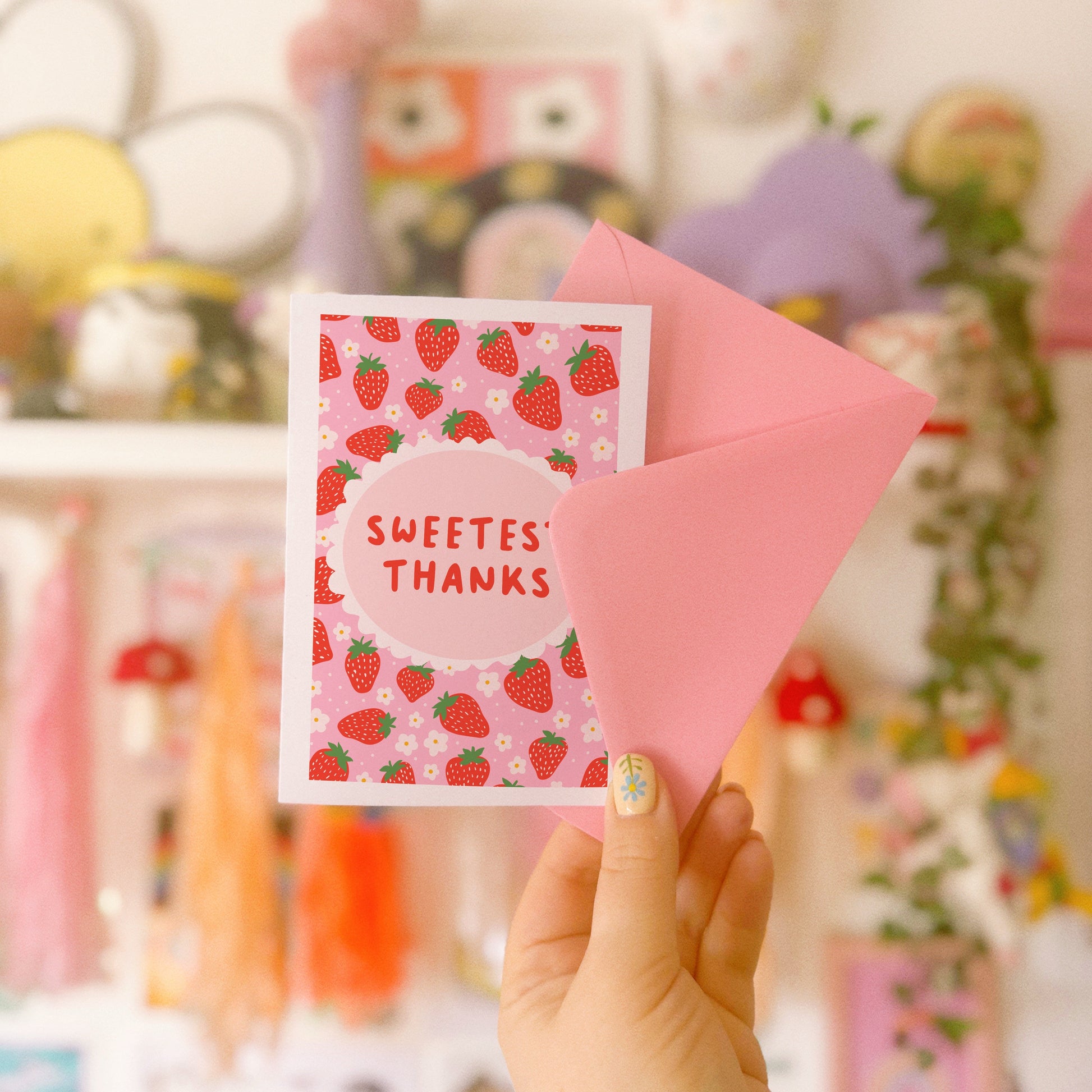 A thank you card with a strawberry pattern, and a small oval in the centre with the text 'Sweetest Thanks' in the centre.