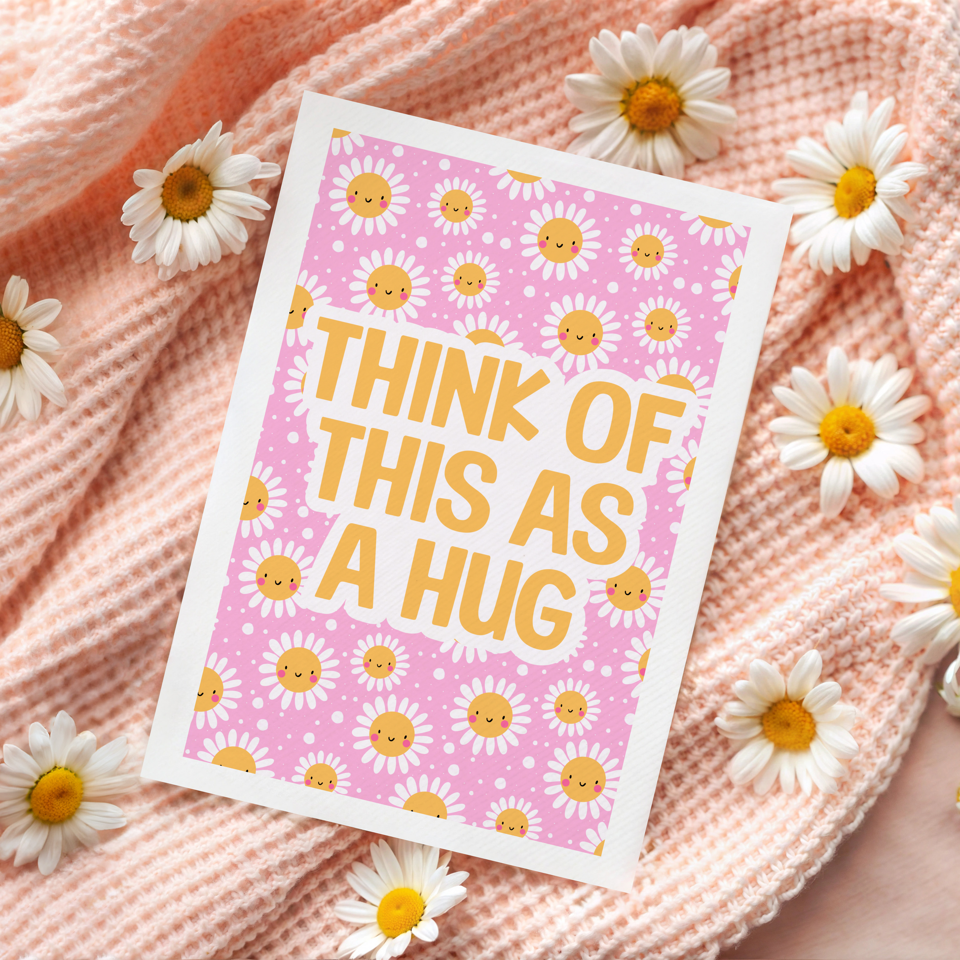 A bright pink and yellow greetings card, with a smiling daisy pattern. The text on the card reads 'think of this as a hug'.