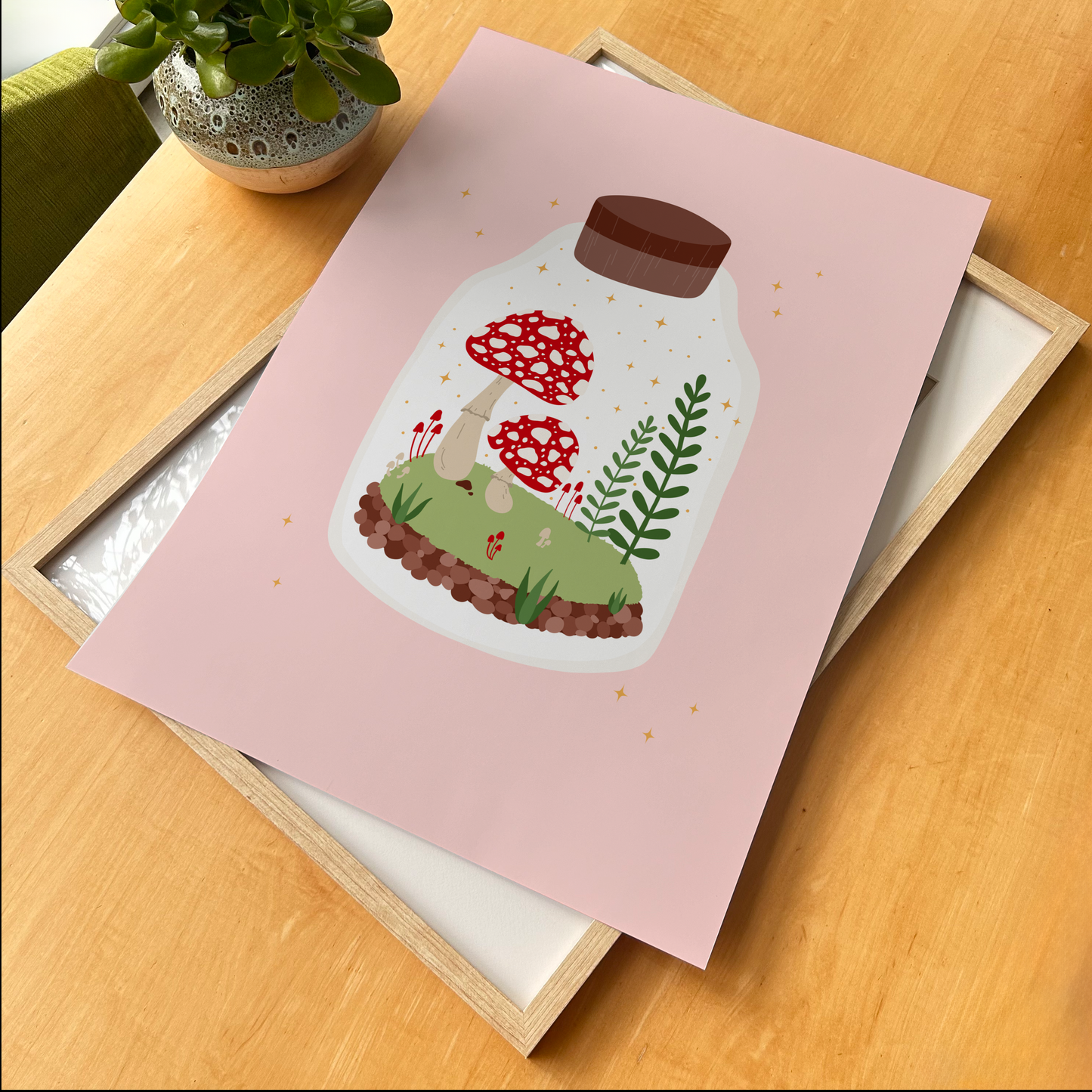 An illustration of two toadstool mushrooms and greenery, in a glass terrarium, on a pink background.
