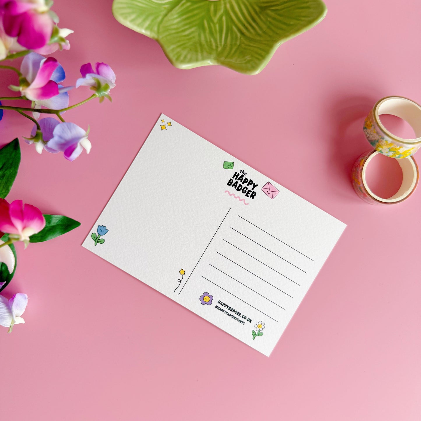 Note card with decorative border on a pink background with flowers and tape.