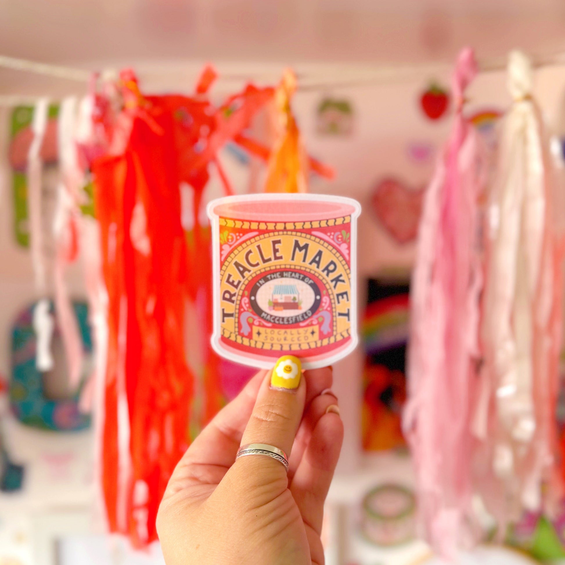 A holographic sticker of a jar of treacle, but it has been illustrated to represent the Treacle market which takes place once a month in the town of Macclesfield.