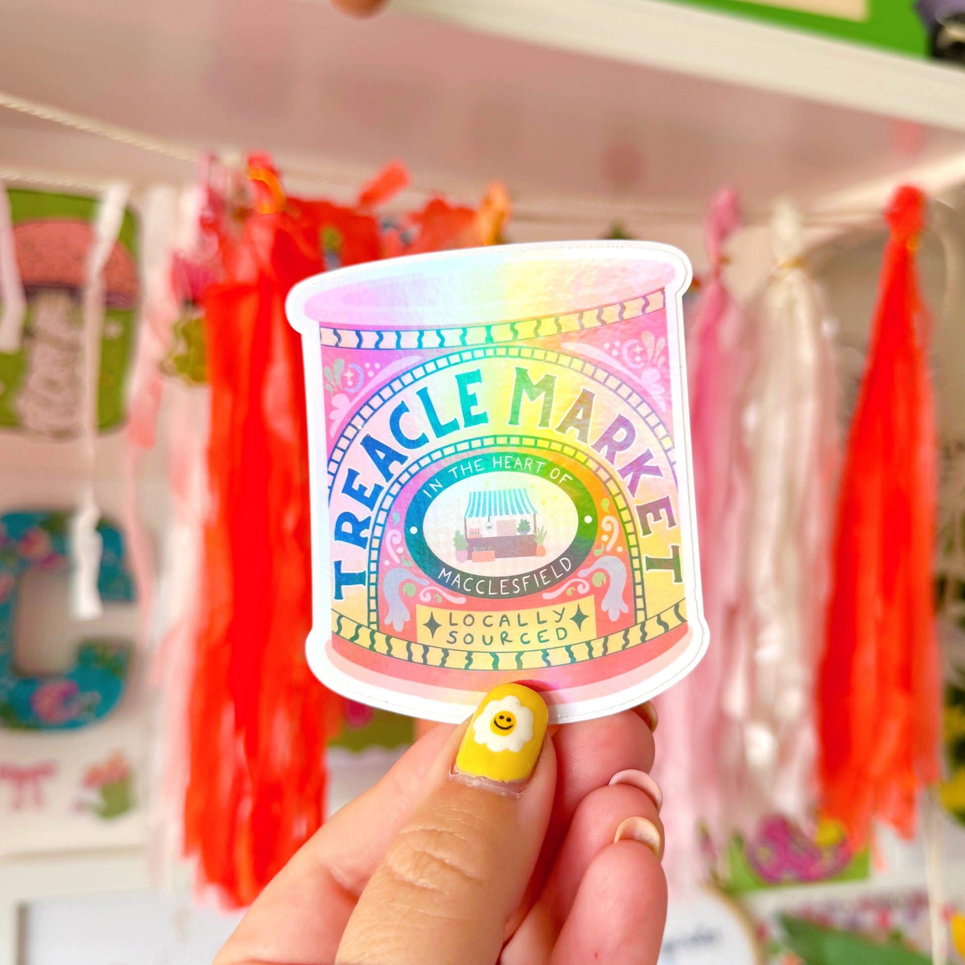 A holographic sticker of a jar of treacle, but it has been illustrated to represent the Treacle market which takes place once a month in the town of Macclesfield.