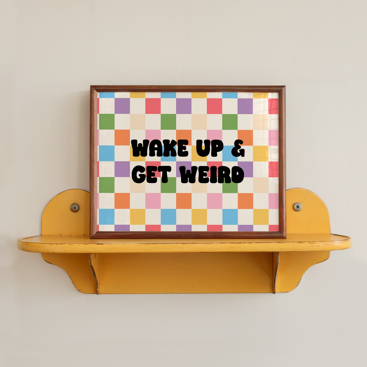 A bright and colourful print, with a checkerboard background and a quote, in black, saying 'wake up and get weird.'