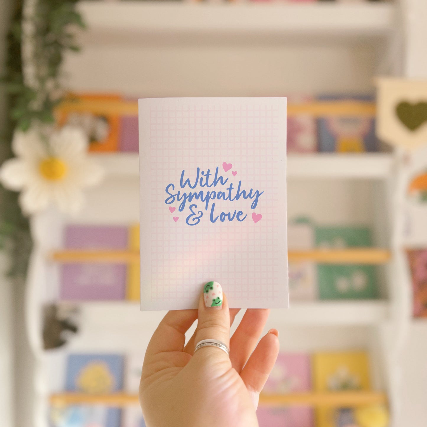 A simple card, with the words with sympathy and love in a blue script font surrounded by small pink hearts.