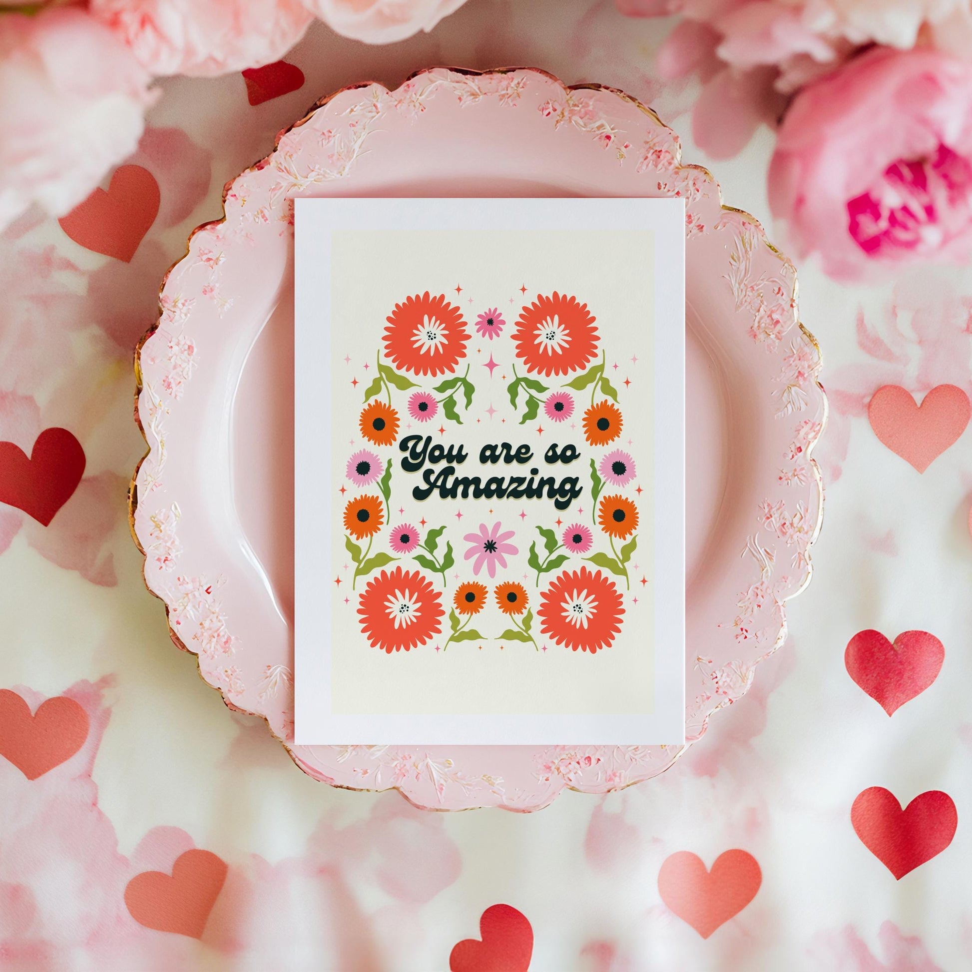 A greetings card with a cream background, with a symmetrical green orange and pink floral design. In the centre of the card are the words 'you are so amazing' in black text.