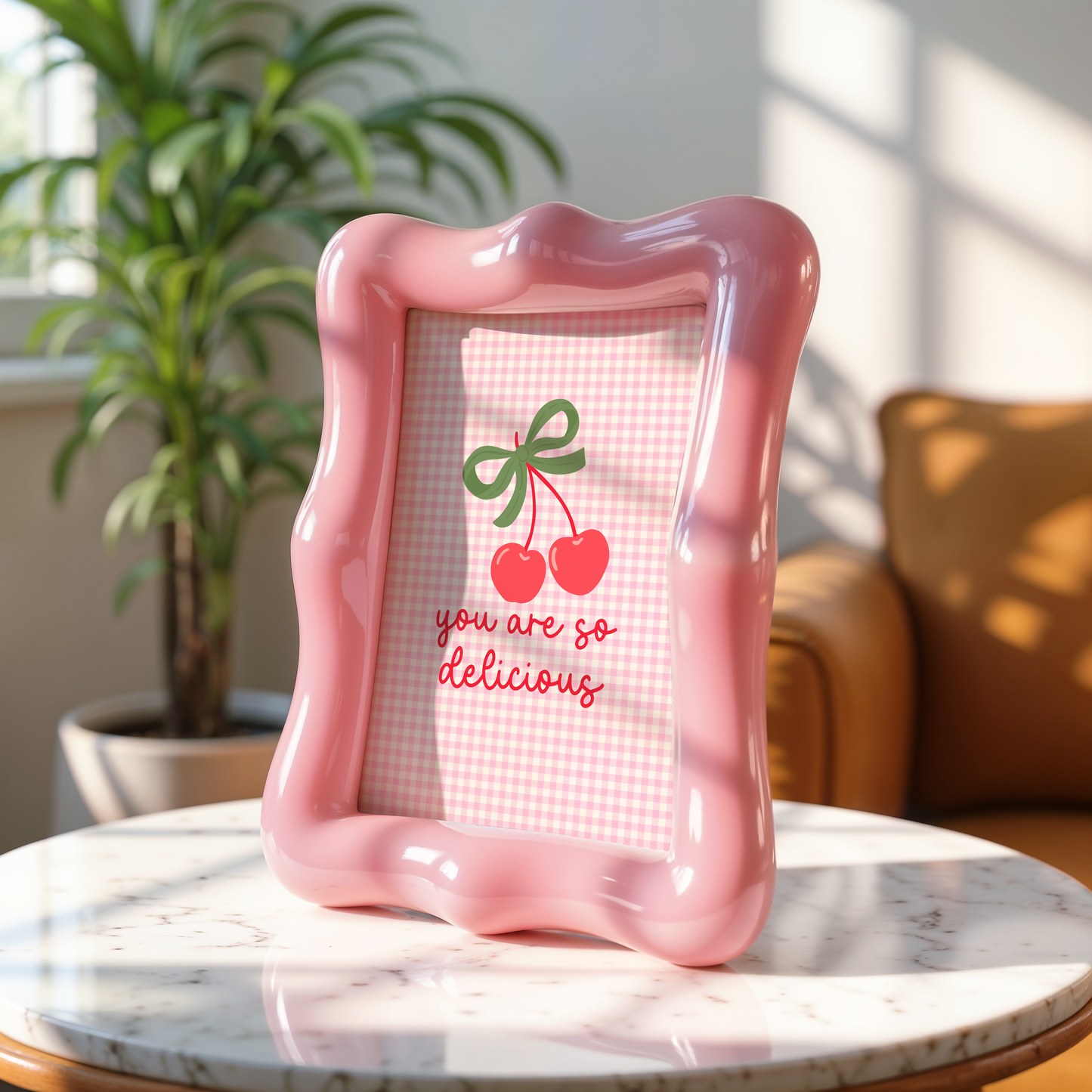 A pink gingham background print, with an illustration of red cherries tied together with a green bow, and the quote saying 'you are so delicious' below.