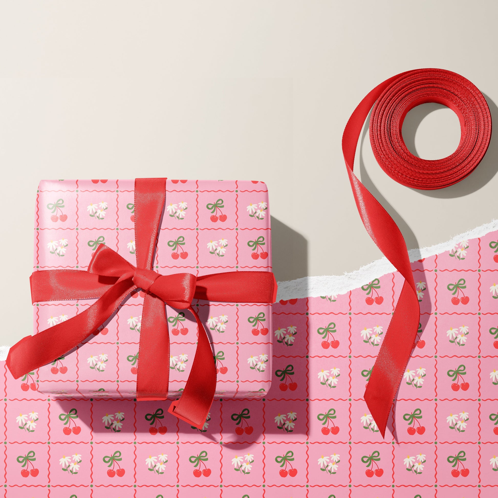A pink patterned gift wrap, with cherries and daisies on.