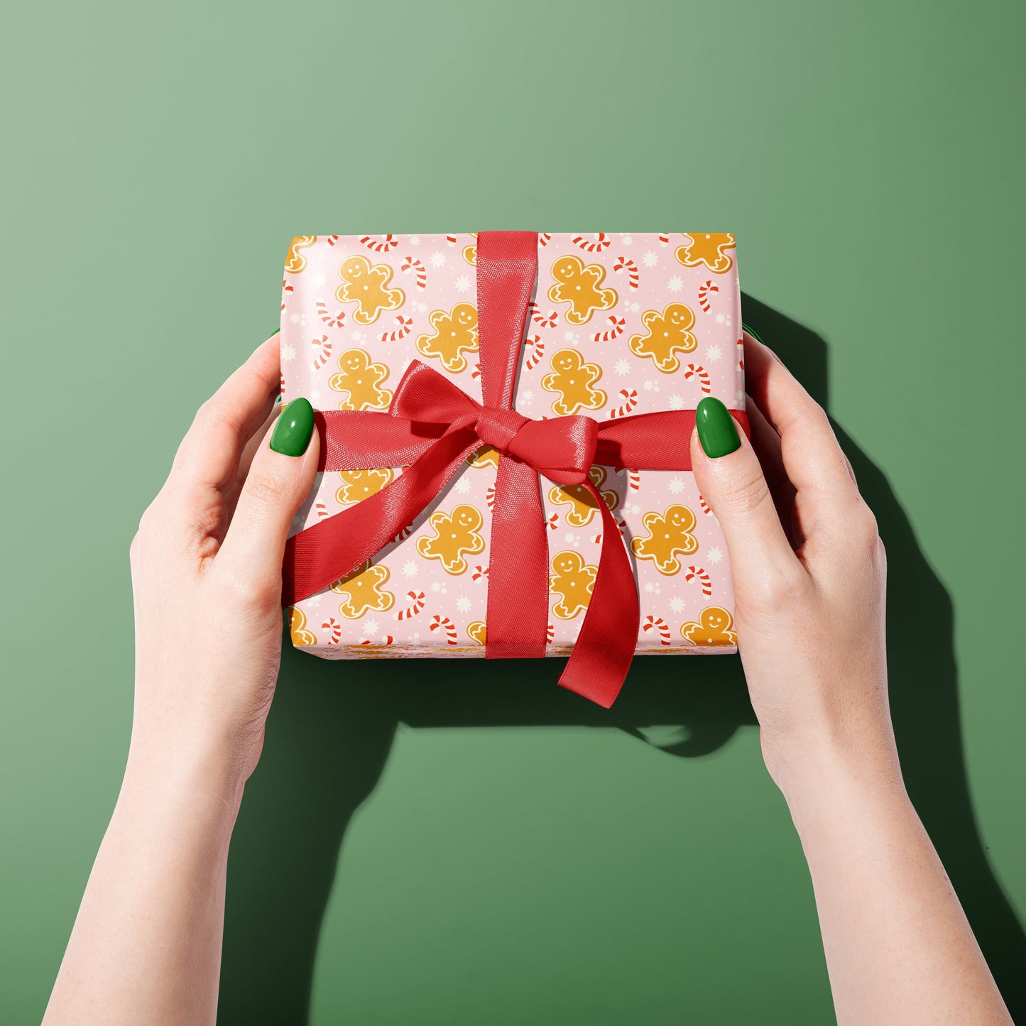 Hands holding a gift box with a red ribbon against a green background