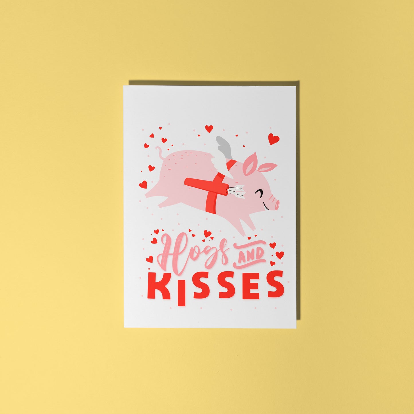A love themed card, with a flying pig dressed as cupid and the words 'Hogs and kisses' underneath.
