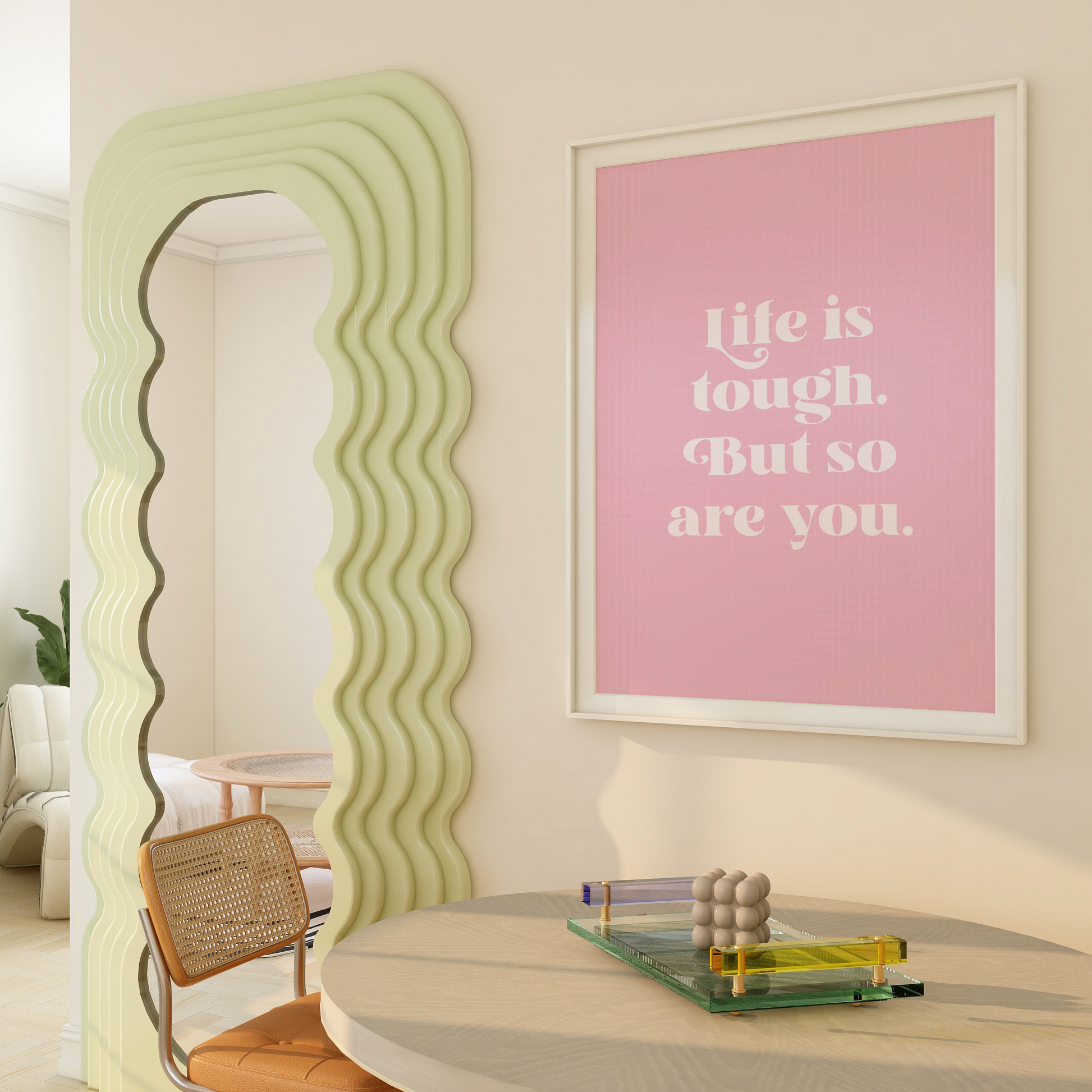 A framed print with a pink background and green frame, containing the text 'Life is tough. But so are you.' in a white font.