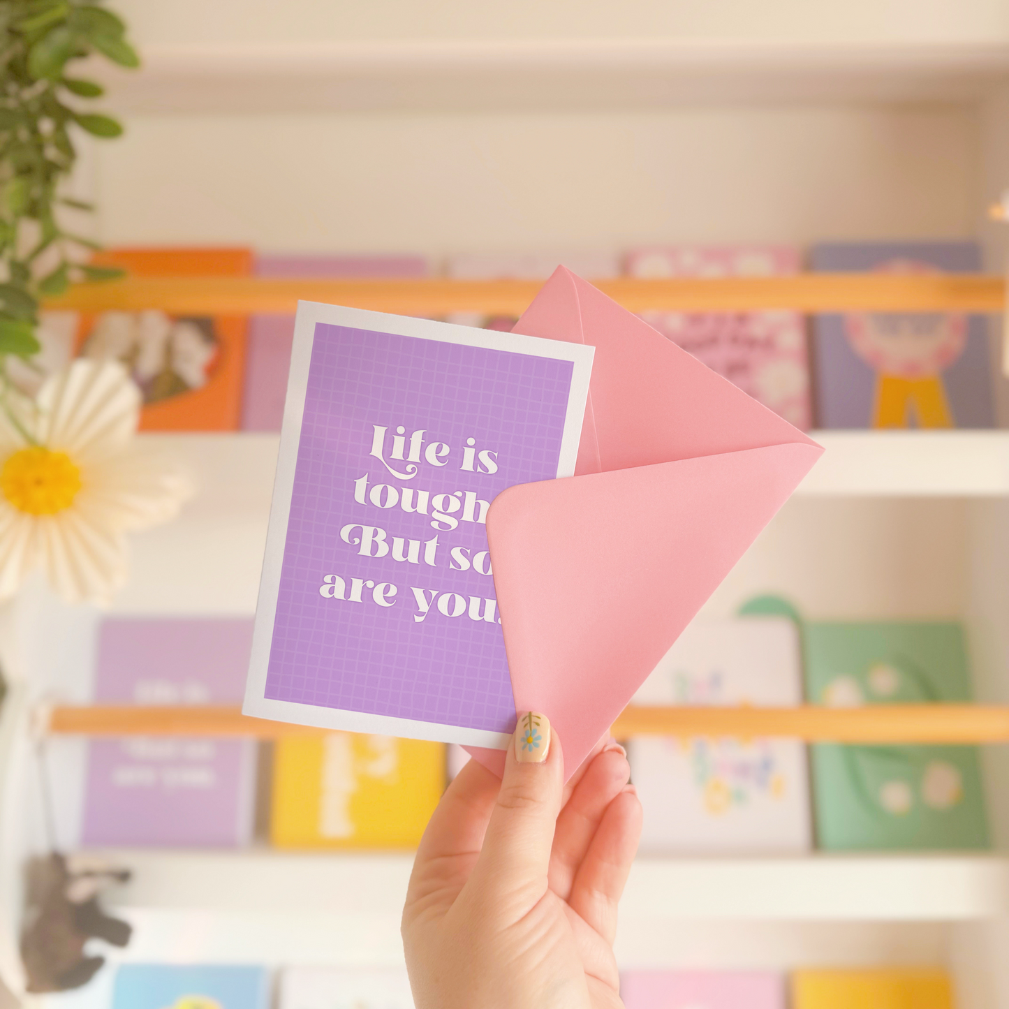 A purple card, with the quote 'life is tough, but so are you' on the front.