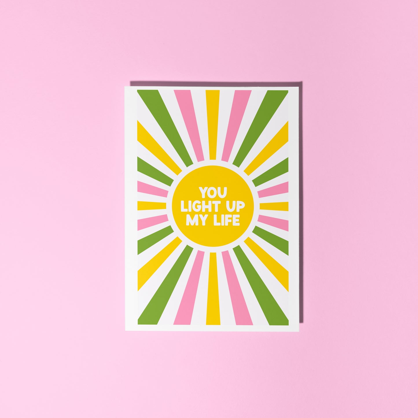 a greetings card with a colourful pink yellow and green sunburst, with the words you light up life in the centre.