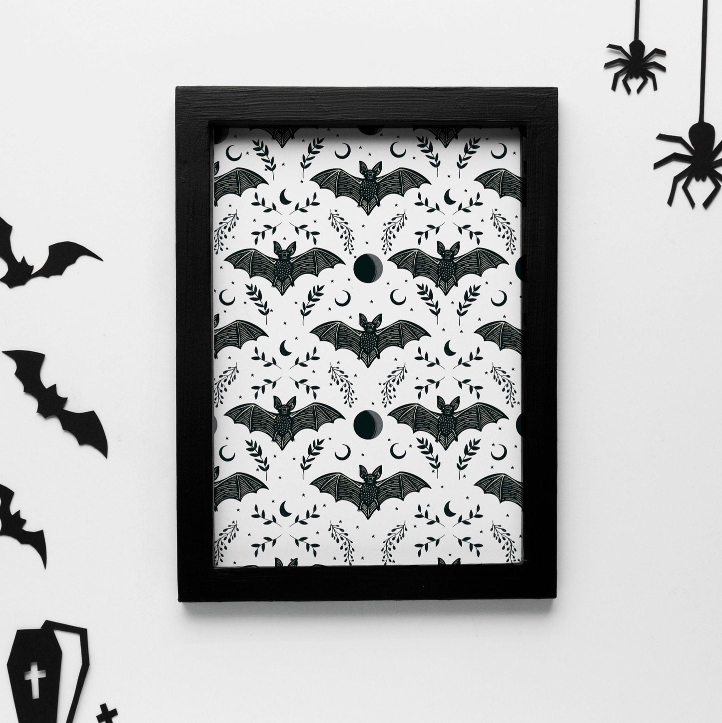A print with a repeating pattern of black bats with moon and floral elements.