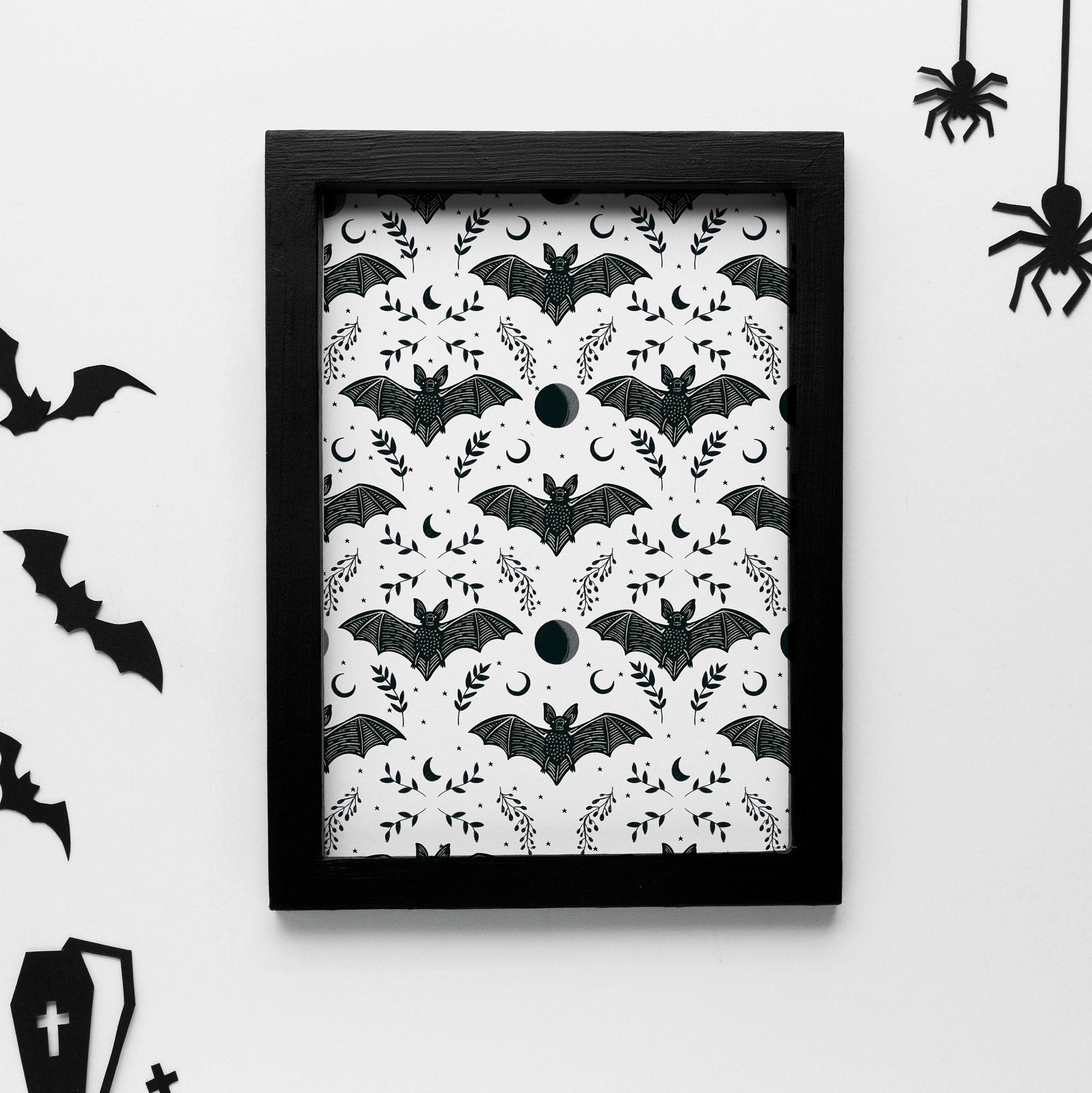 A print with a repeating pattern of black bats with moon and floral elements.