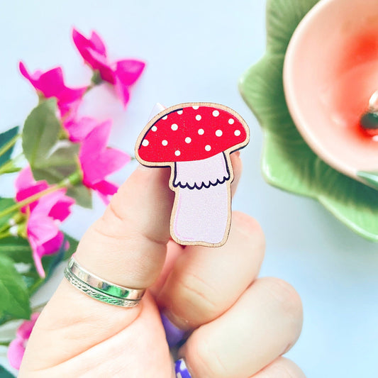 A wooden eco friendly pin badge of a cute skinny mushroom.