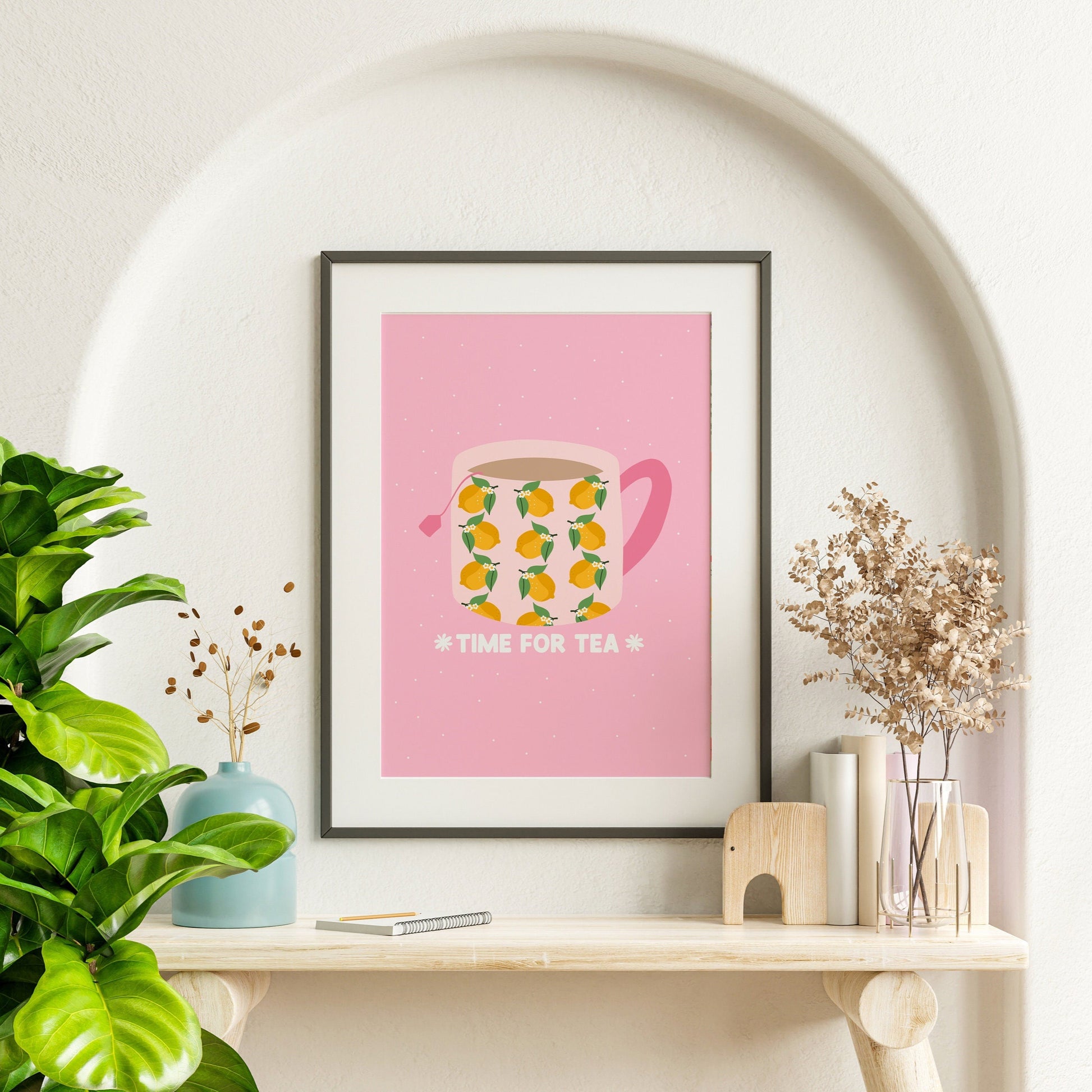 A pink print, with an illustration of a mug filled with tea. The mug has a lemon pattern on it and a pink handle. Underneath the mug are the words 'time for tea', written in white text.