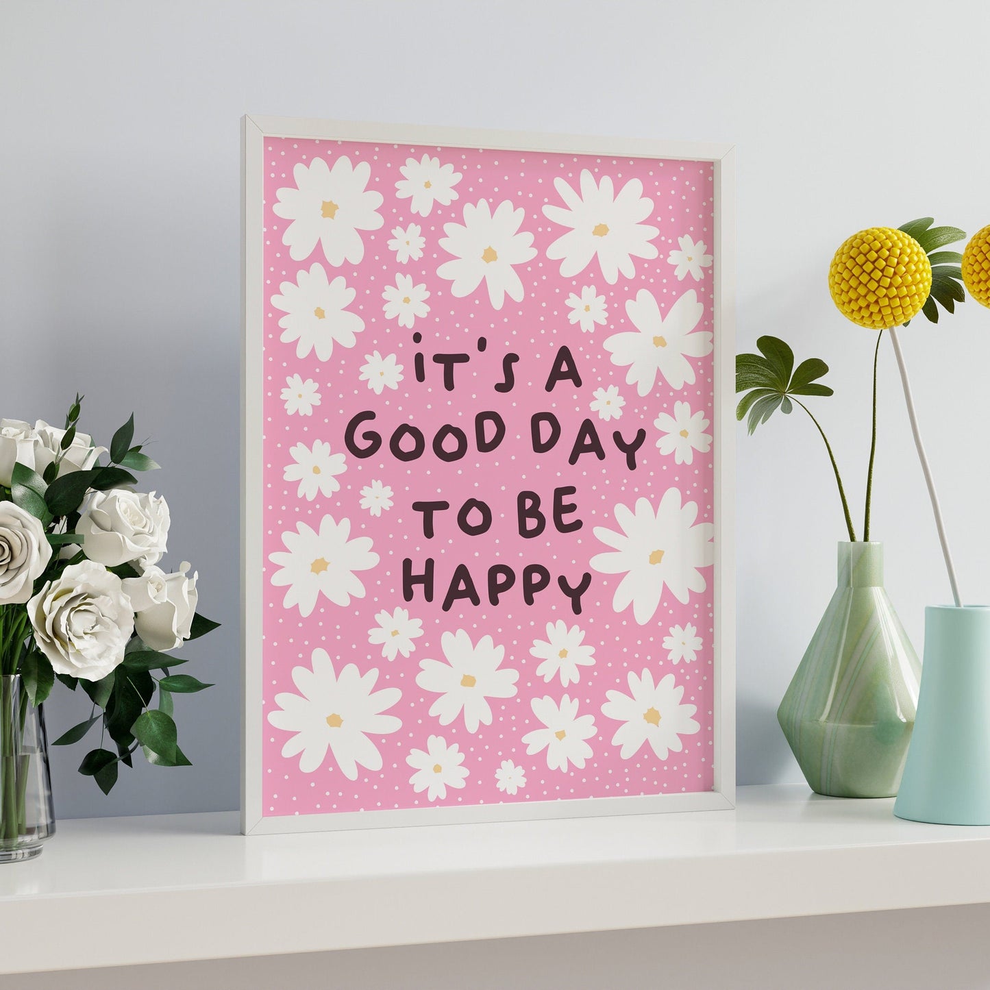 A pink print with several white daisies, surrounding a positivity message of 'it's a good day to be happy'.