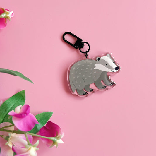 Badger-shaped keychain on a pink background with pink flowers