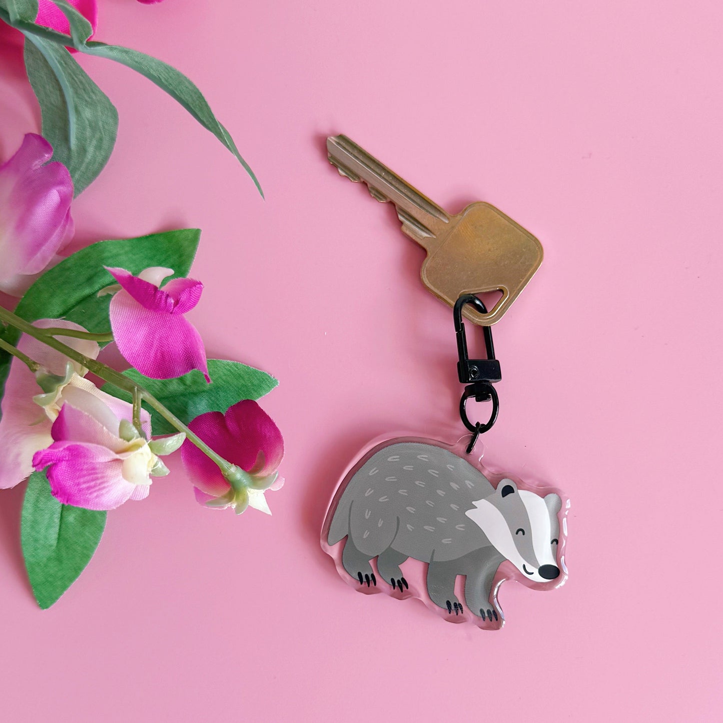 Keychain with a badger design on a pink background with flowers