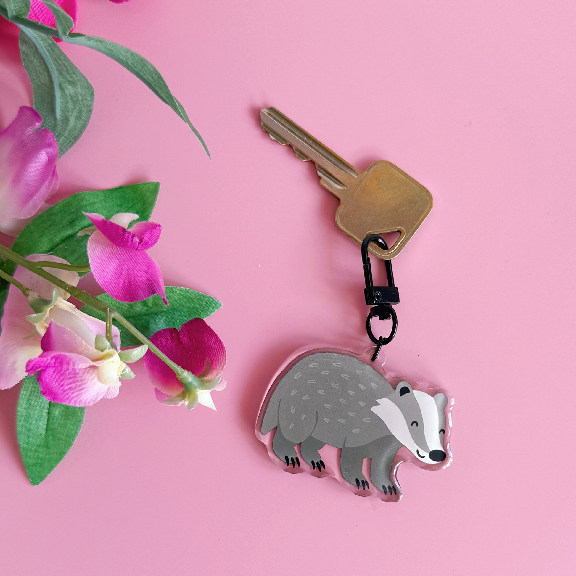 Keychain with a badger design on a pink background with flowers
