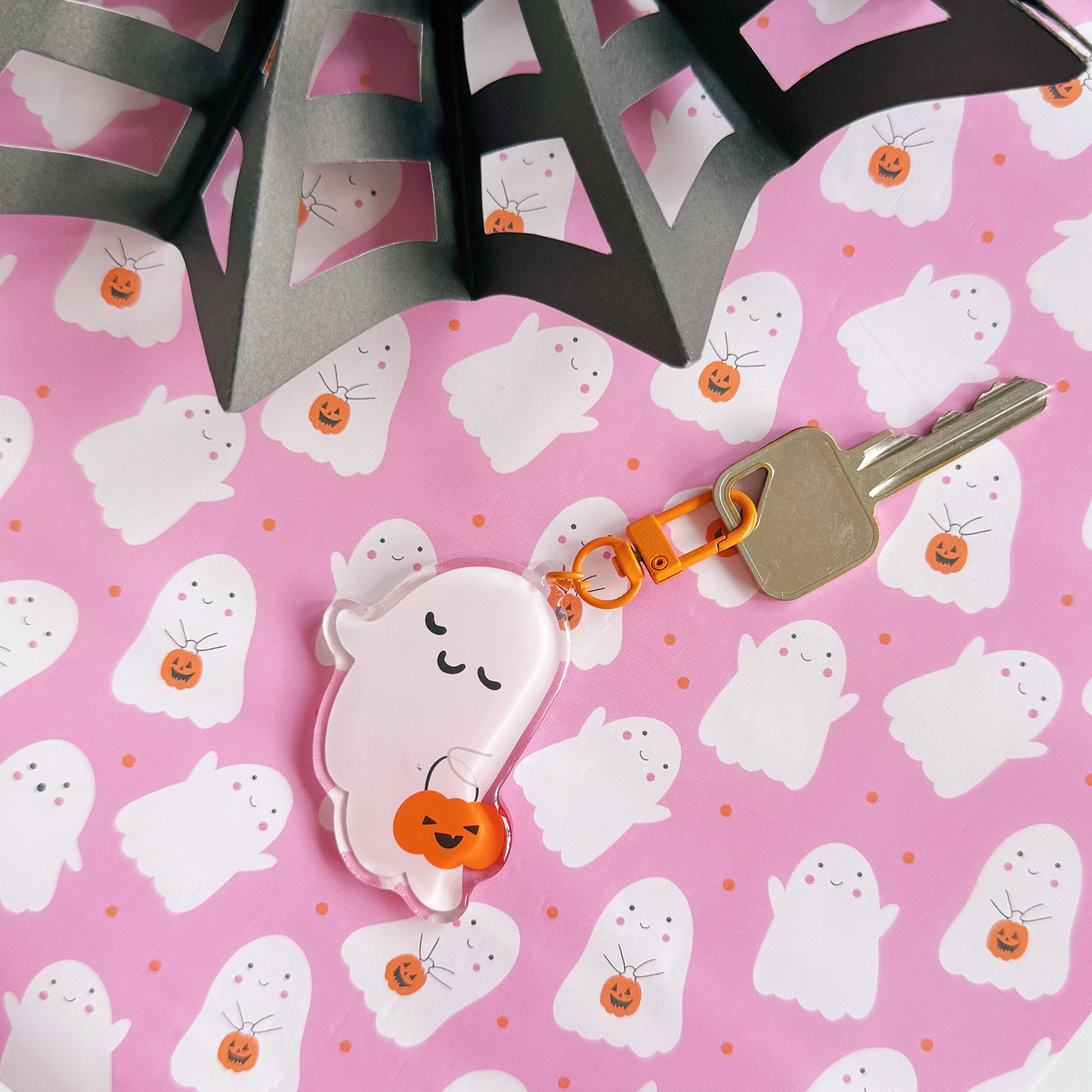 Keychain with a ghost design on a pink Halloween-themed paper