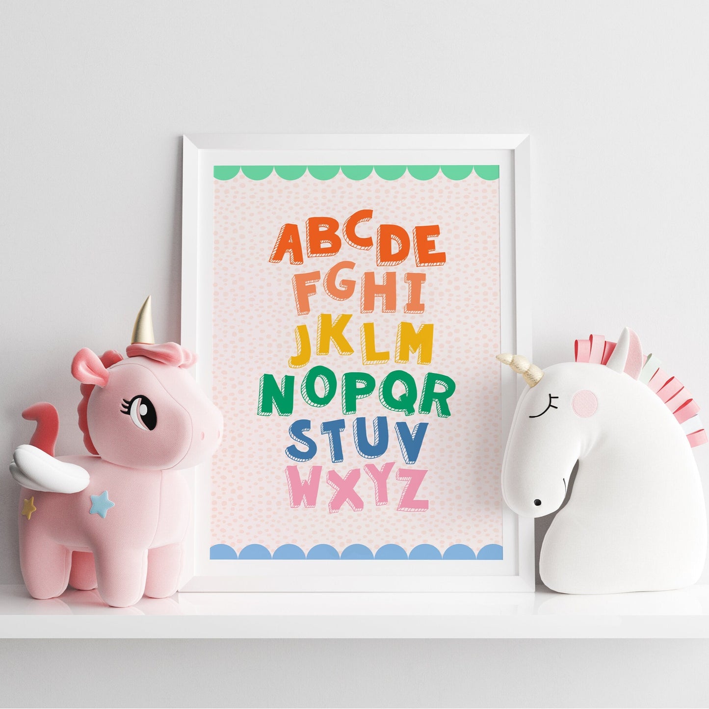 A colourful alphabet print, with a coordinating scallop border, shown in a frame.