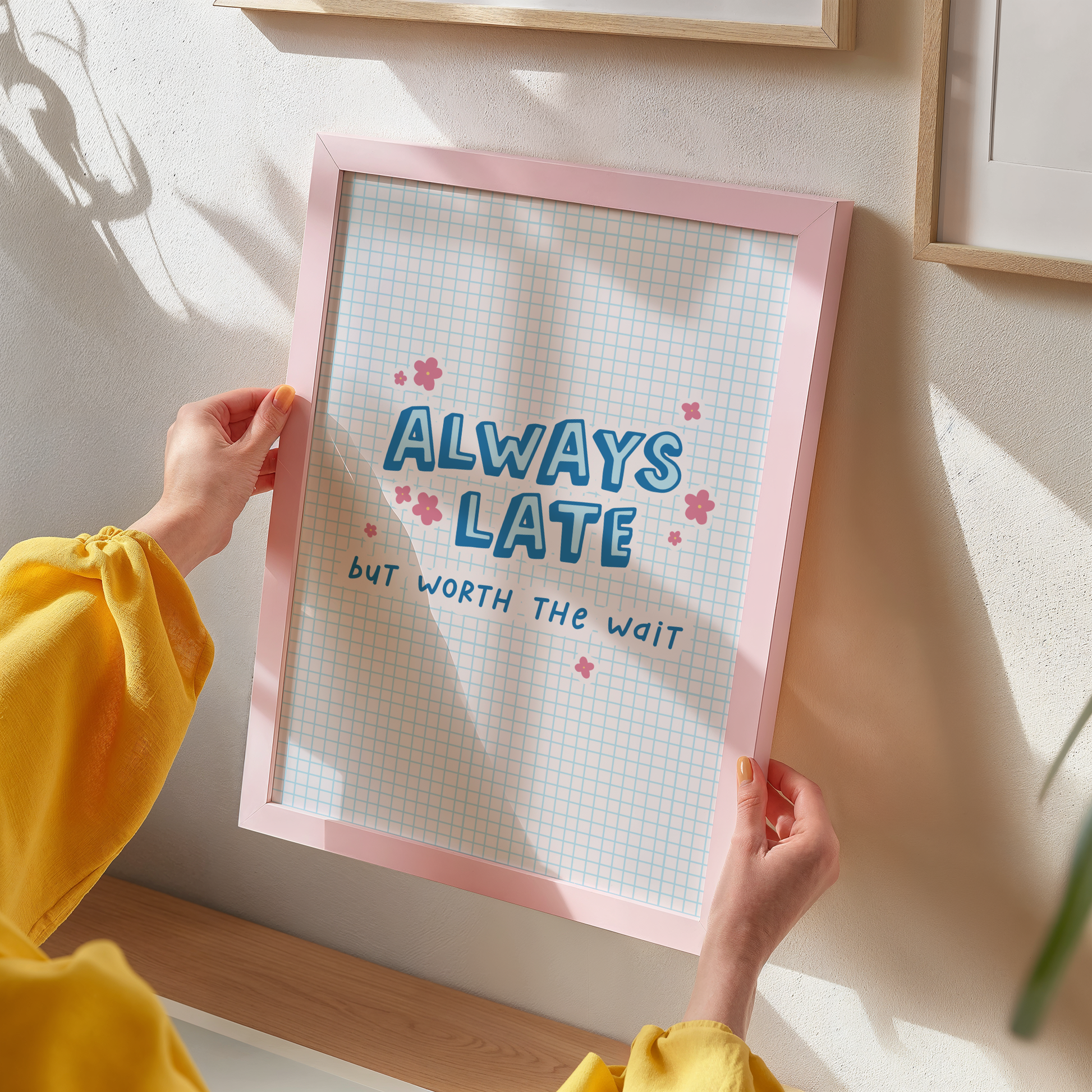 An illustration of a blue print, with a funny quote stating always late but worth the wait, shown in a frame.