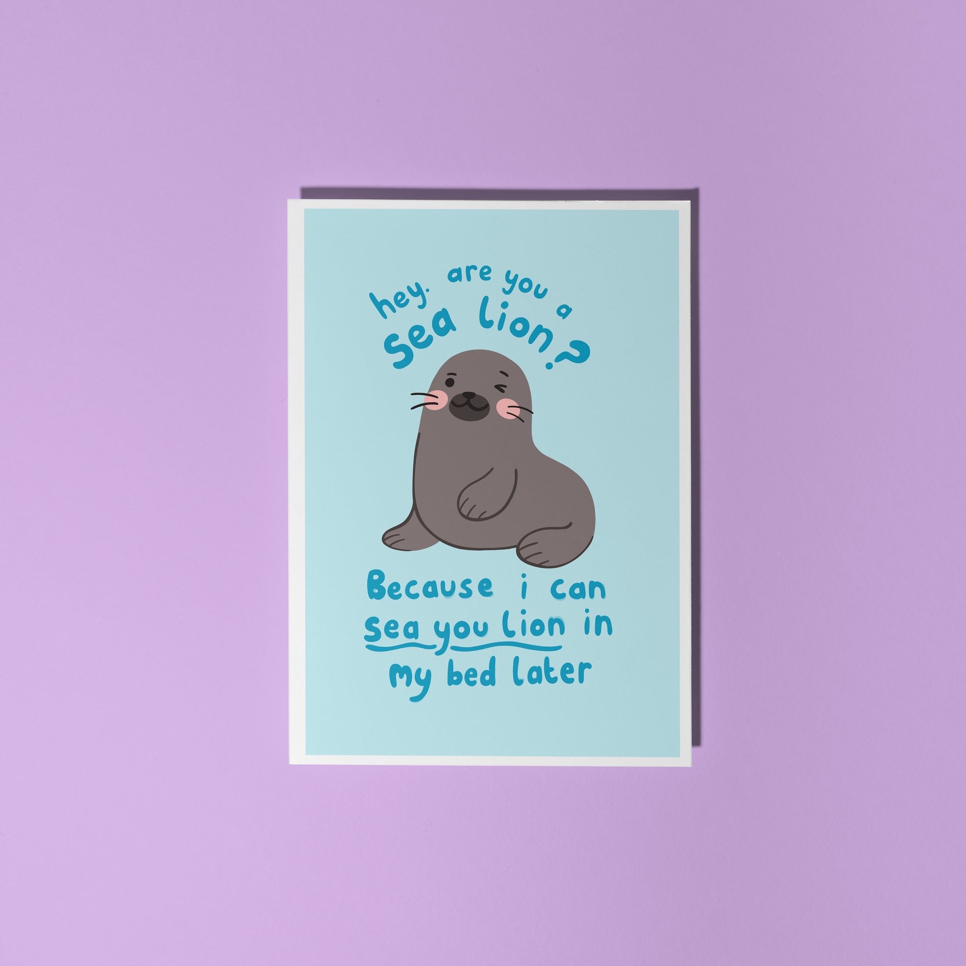 A blue greeting card with an illustration of a sea lion on the front. There is a cheeky quote on the front, using a pun, saying 'are you a sea lion? because I can sea you lion in my bed later'.