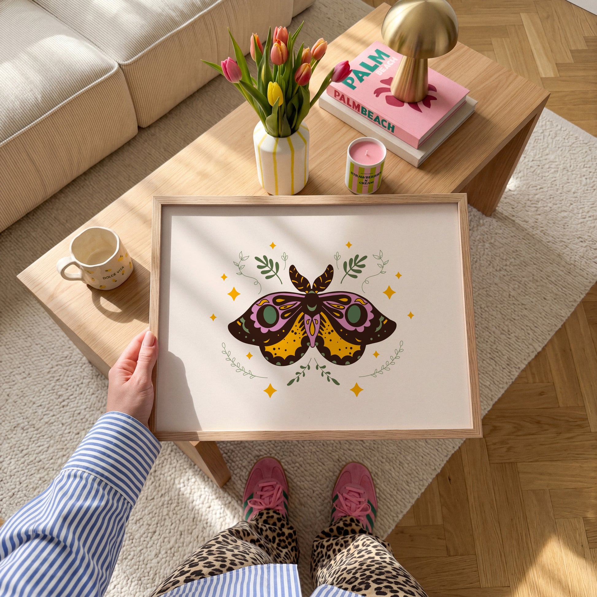 An illustration of a moth with ornate patterns on its wings. The colours are purple, mustard and teal with a neutral warm beige background.