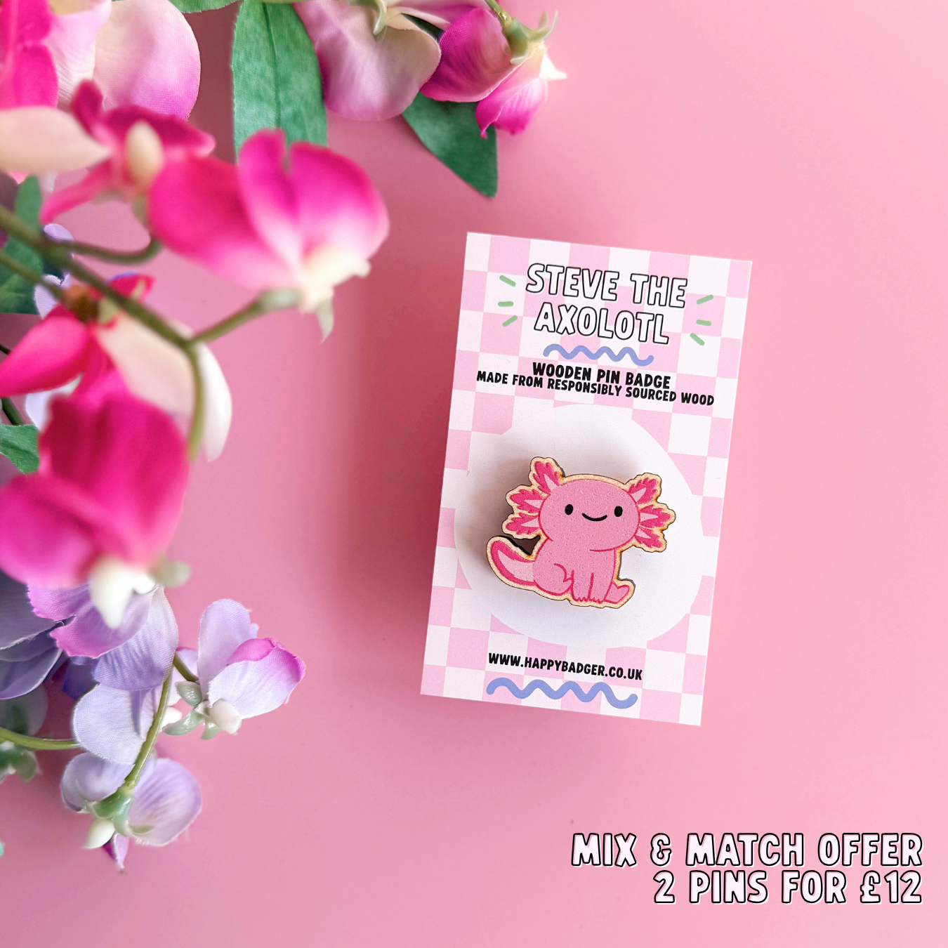 A wooden pin badge with a glossy finish, featuring an illustration of a pink axolotl.