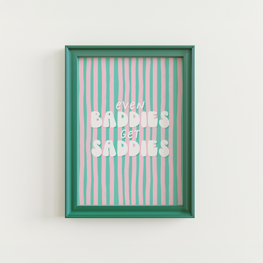 A funny quote print saying Even Baddies Get Baddies Print on a teal and pink striped background.