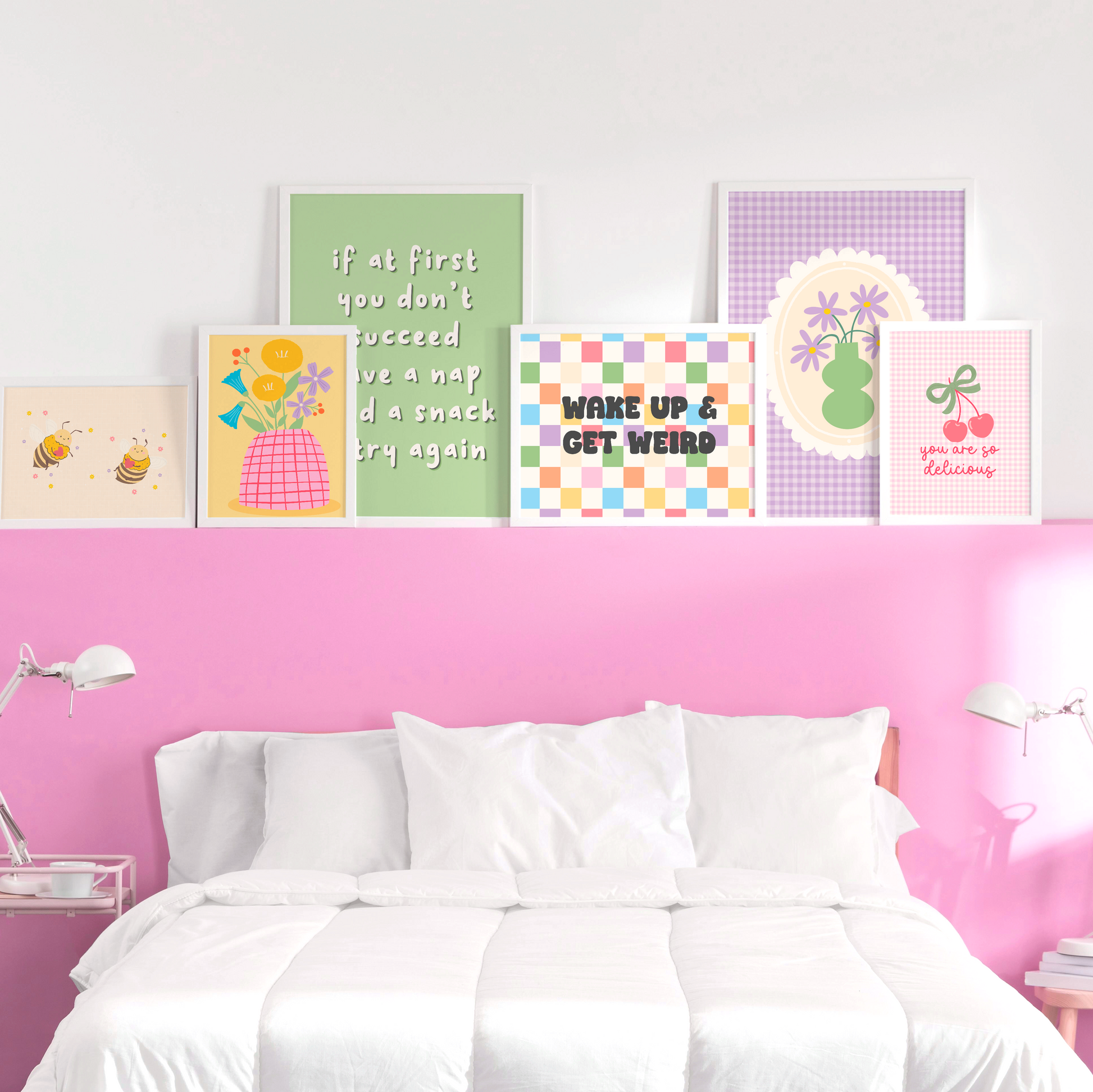 Colourful wall art prints on a pink wall above a bed.