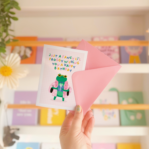 A cute birthday card with an illustration of a fancy looking frog holding a birthday present and the text reads 'just a fancy little froggy wishing you a happy birthday'