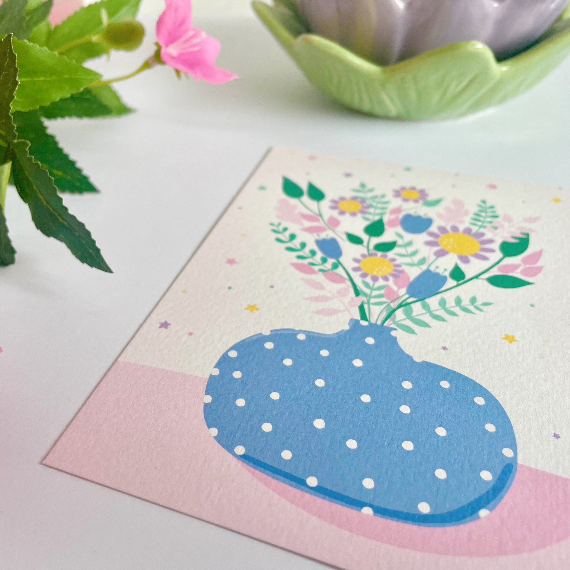 A textured postcard, featuring a blue vase with multicoloured flowers in it.