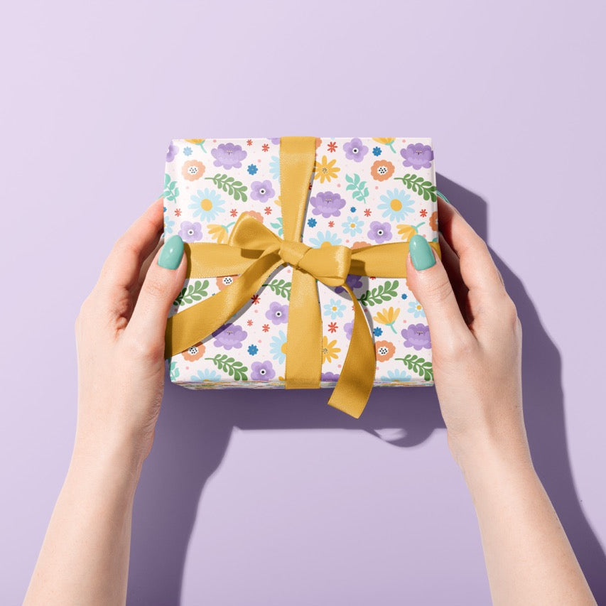 A gift wrapped present, wrapped up in bright floral gift wrap from The Happy Badger.