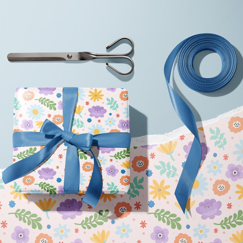 A gift wrapped present, wrapped up in bright floral gift wrap from The Happy Badger.