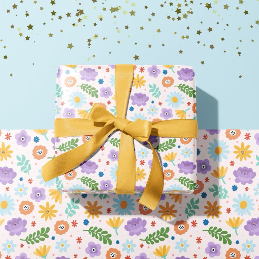 A gift wrapped present, wrapped up in a bright floral print gift wrap from The Happy Badger.