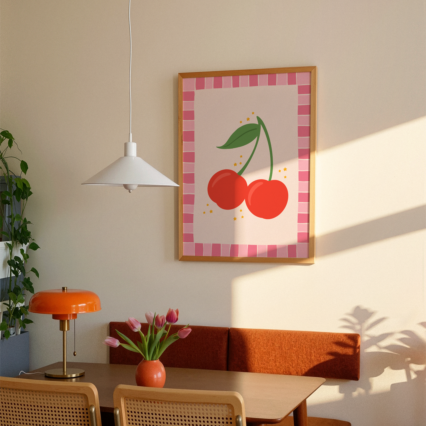 A print with an illustration of a pair of cherries, on a soft pink background surrounded by a bright pink hand drawn border.