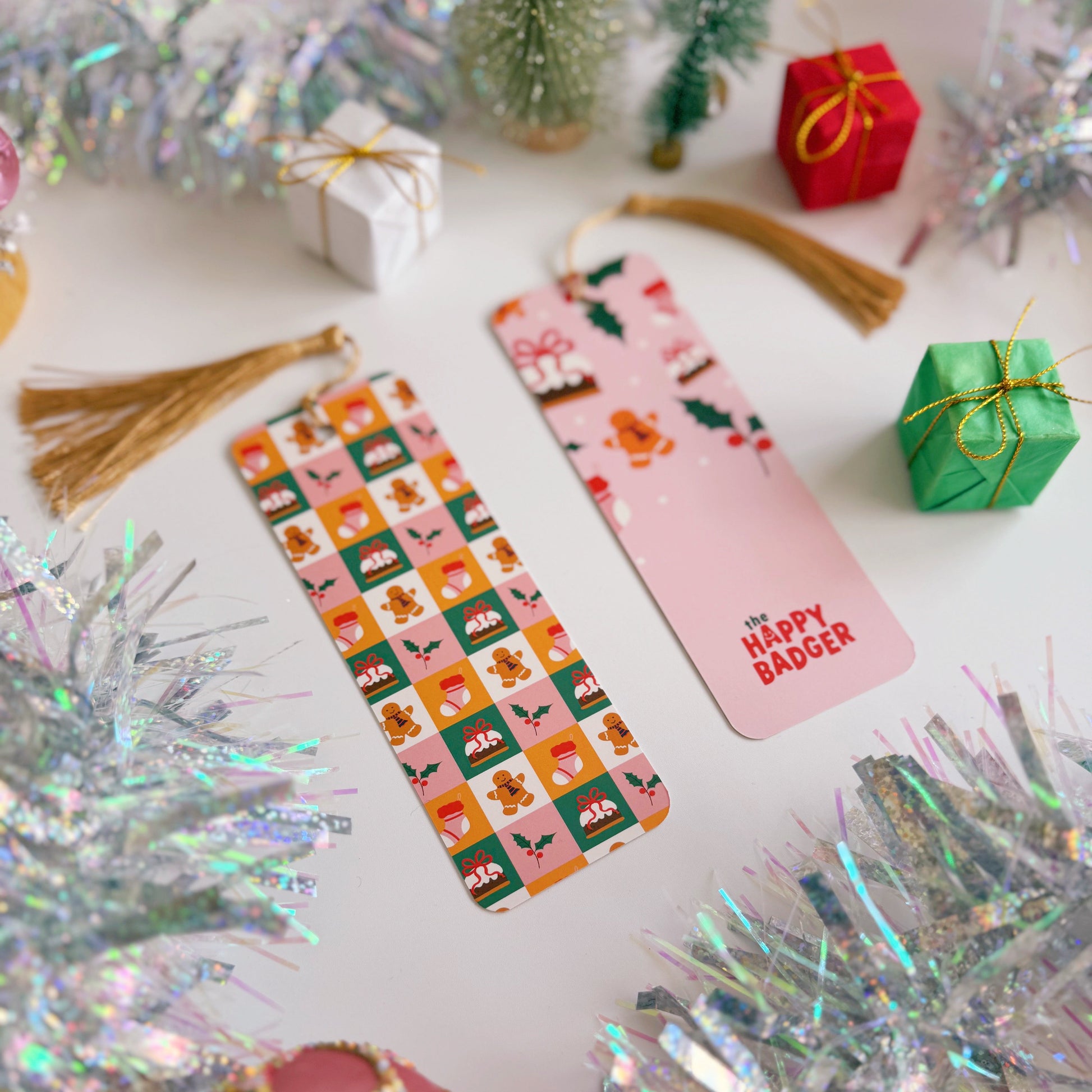 A colourful bookmark with Christmas designs on the front and back, on a festive background with tinsel and small gifts.