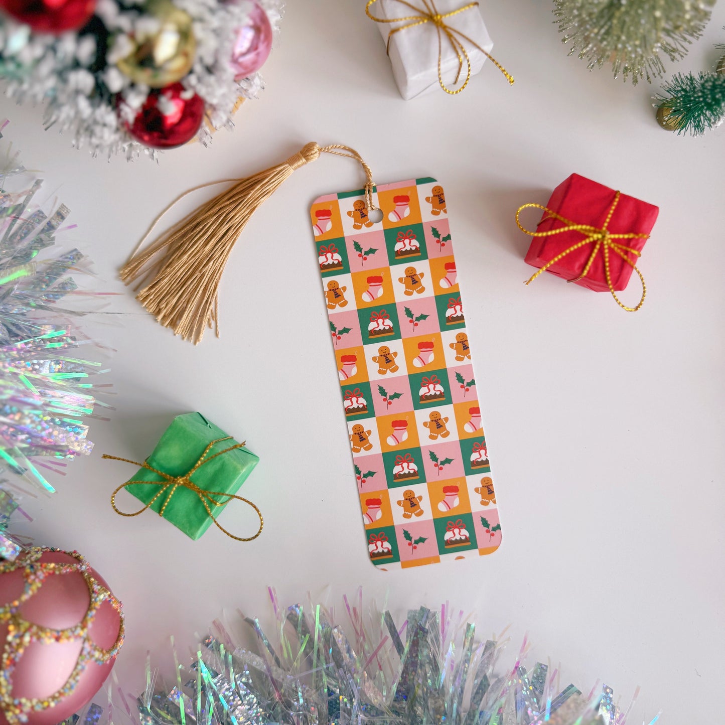 Christmas bookmark with festive design surrounded by Christmas decorations on a white surface