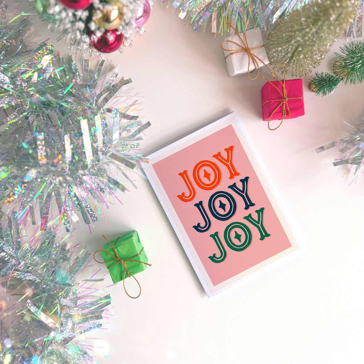 A Christmas card with the word 'JOY' written on the front in three different festive colours.