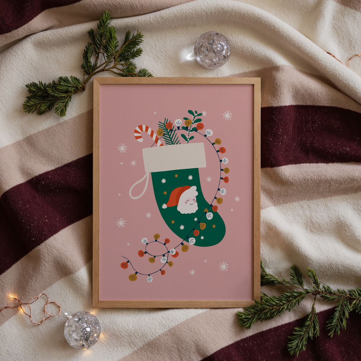 A Christmas illustration print featuring a green traditional stocking with a Father Christmas design, with fairly lights, candy canes and mistletoe inside the stocking.