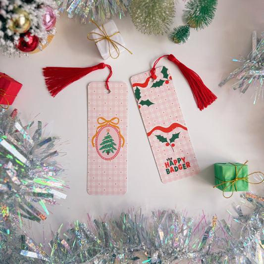 A Christmas-themed bookmark with tassel, both the front and back sides are shown, on a festive background with tinsel and small trees.