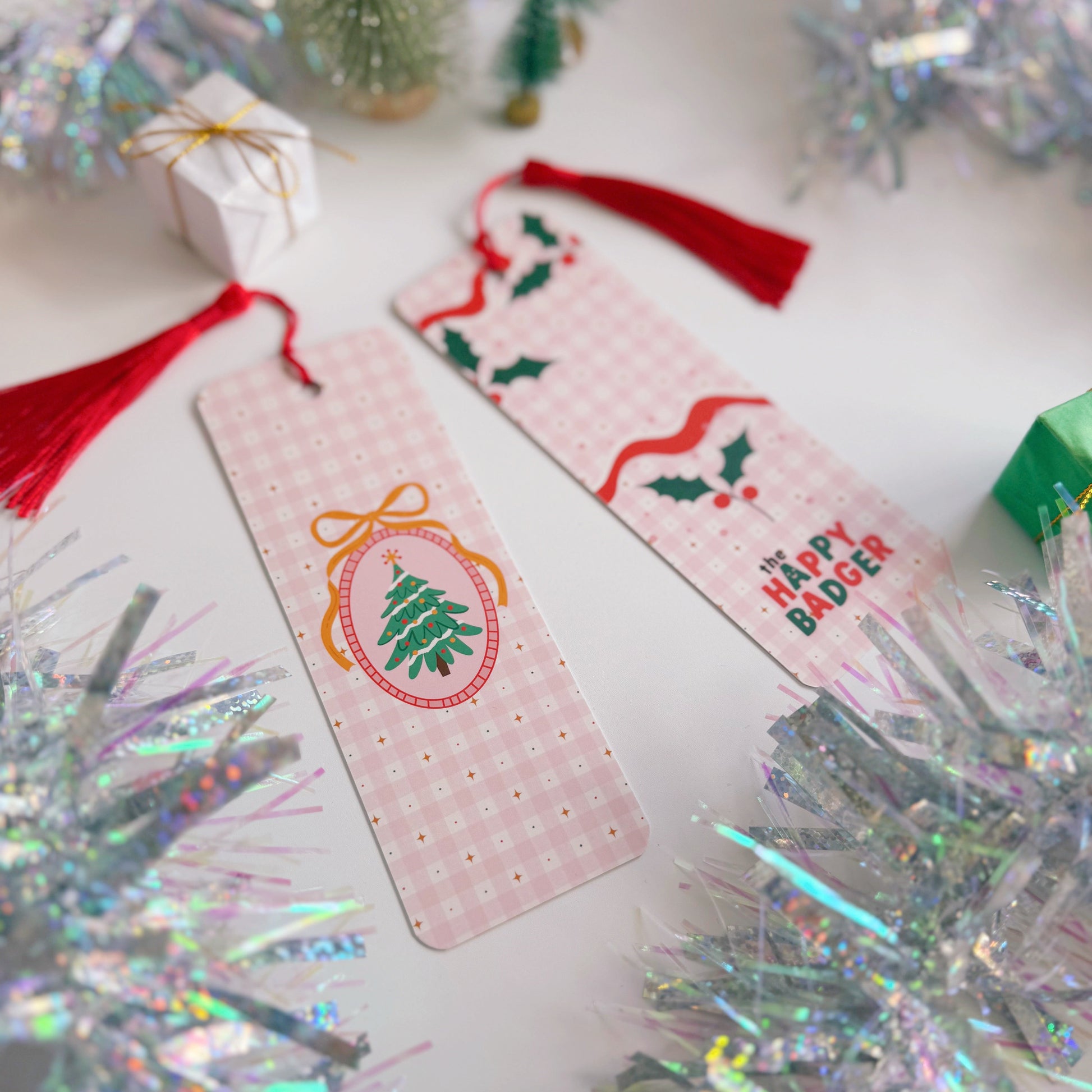A Christmas-themed bookmark on a decorative surface with tinsel and small trees.