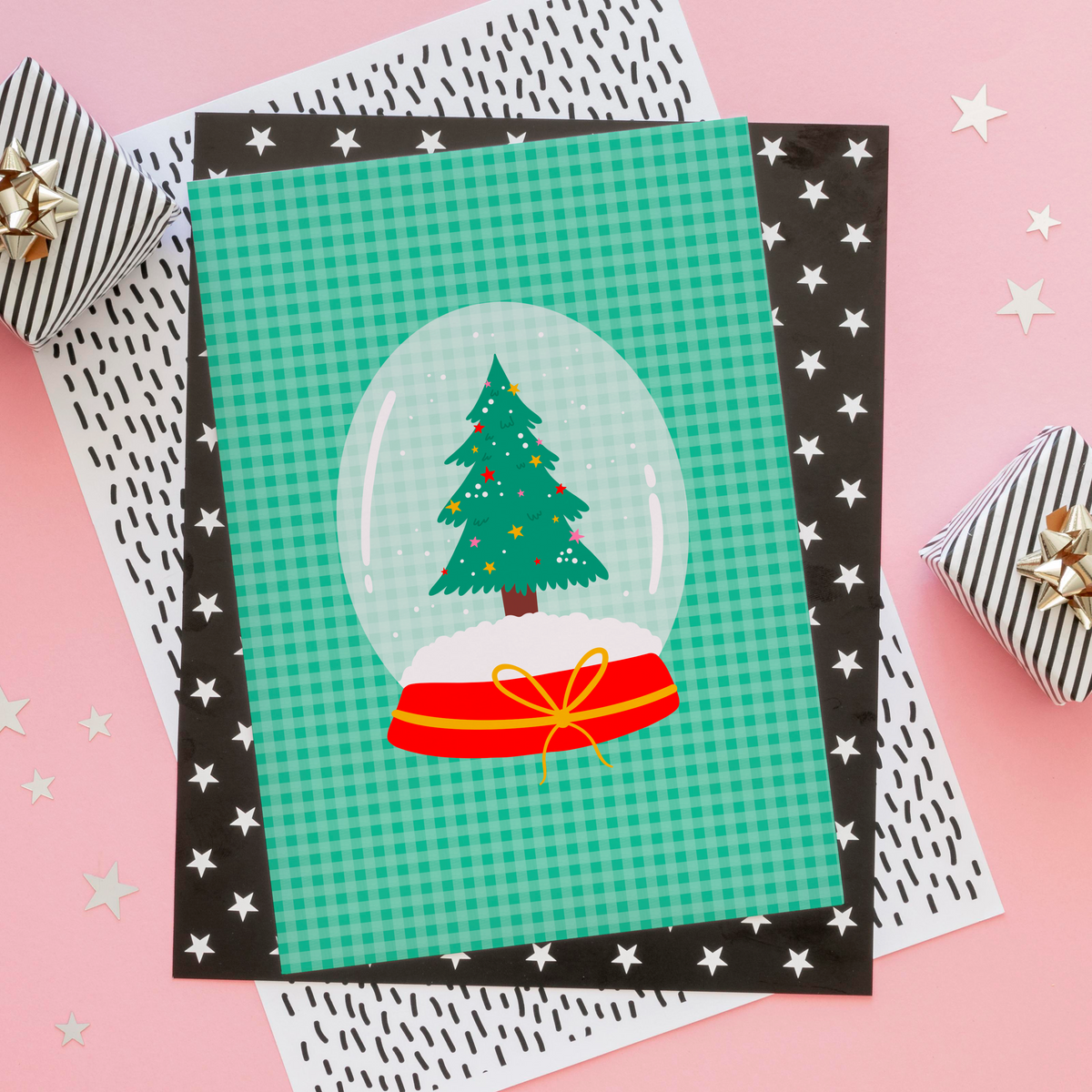 An illustrated Christmas print, featuring a Christmas tree inside a snow globe, set on a green gingham background.