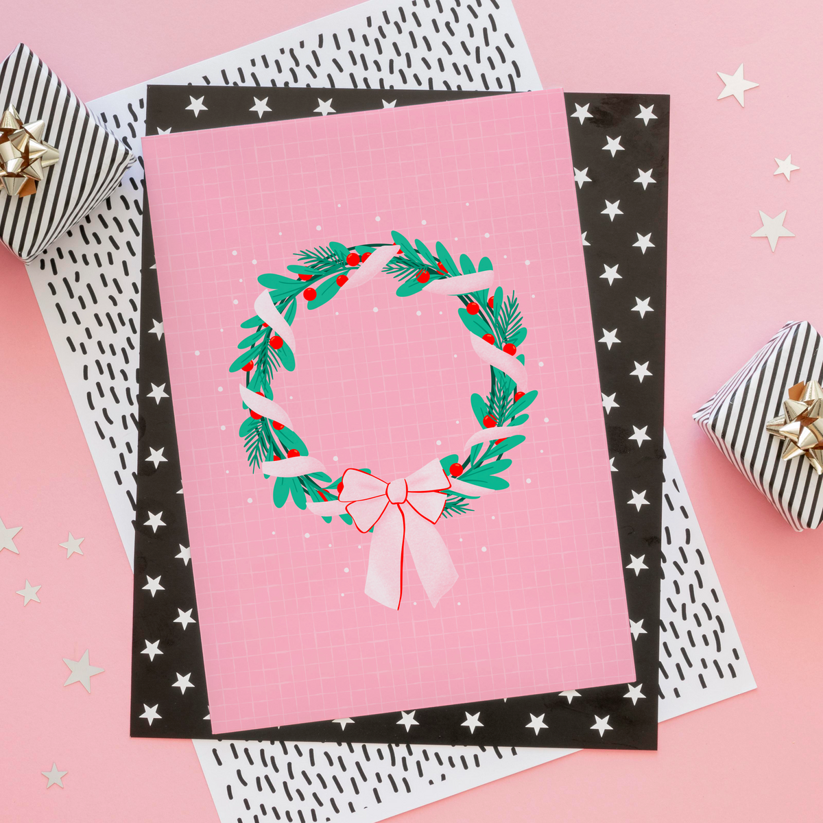 A bright pink christmas print featuring an illustration of a wreath wrapped in ribbon.