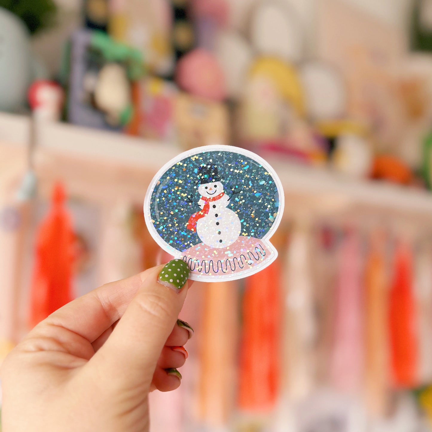 Hand holding a snowman sticker with a colorful background