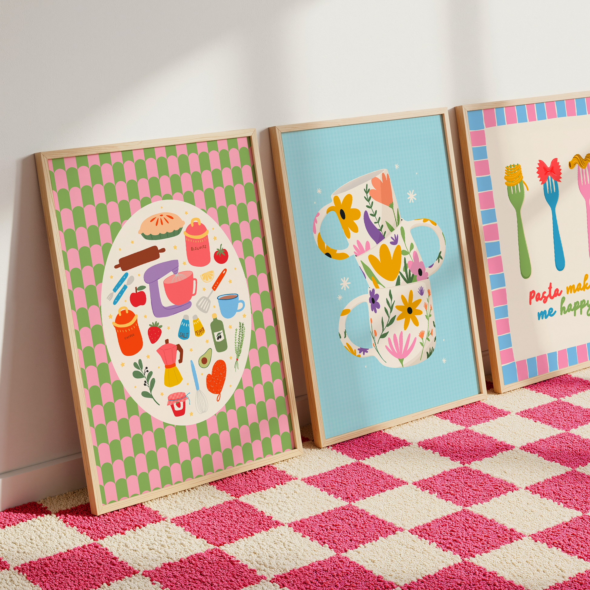 Three colourful kitchen prints shown leaning against a wall on a pink checkerboard carpet.