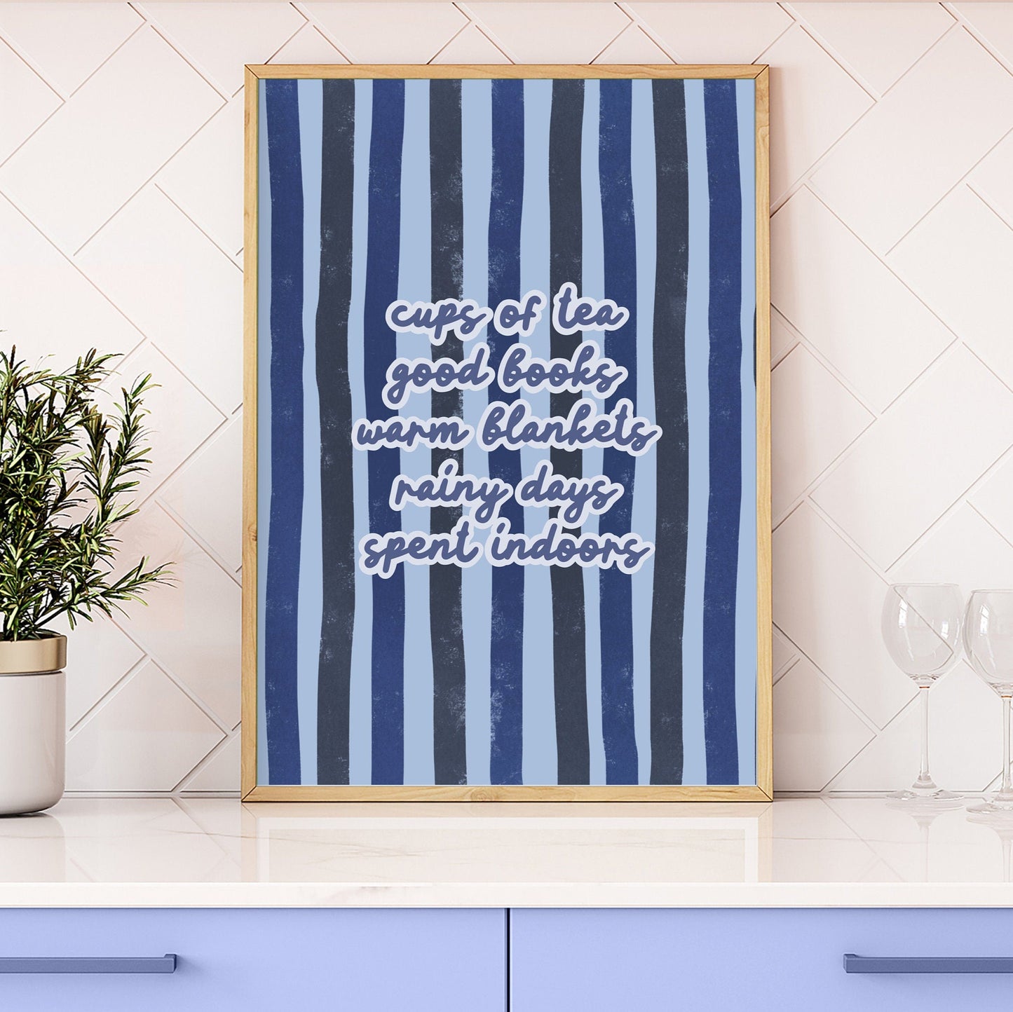 An cosy autumn quote print, on a blue striped background, shown in a frame.