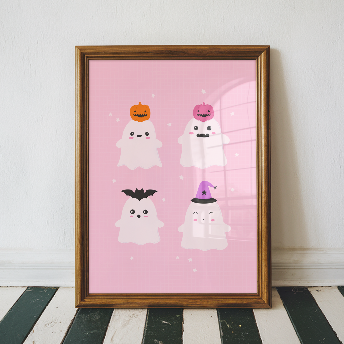 A pink Halloween illustration print featuring four cute ghosts with different Halloween themed hats on their heads.